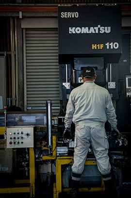 工場内の機械を操作している作業員の写真です。